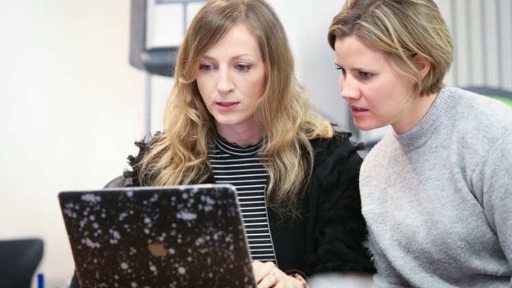 Two people looking at a laptop screen together.